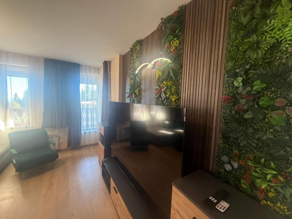 un salon avec une télévision et un mur de fleurs dans l'établissement Апартаменти Pamporovo Dream в Гранд Ризорт Пампорово, à Pamporovo