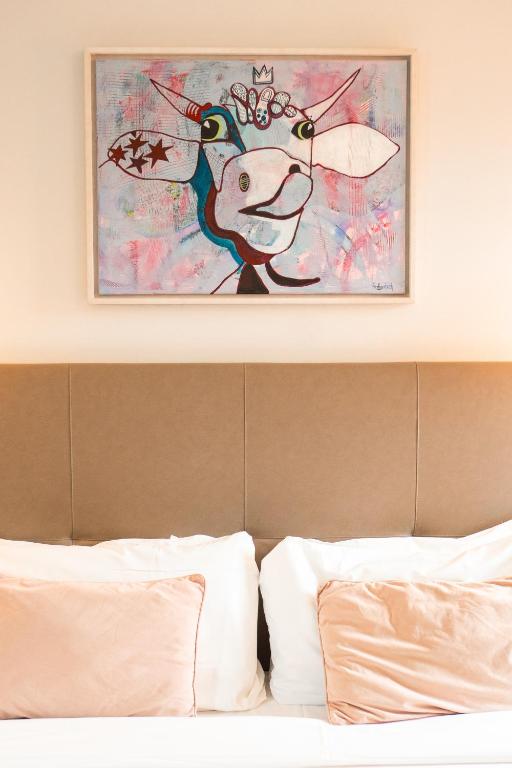 a painting of a cow is above a bed at Benaco36 in Torri del Benaco