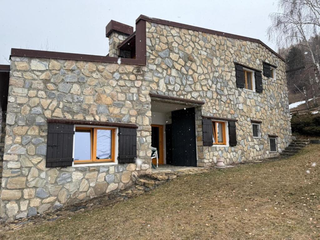 a stone house with a black door and windows at Alpine Dream Apartments in Bormio