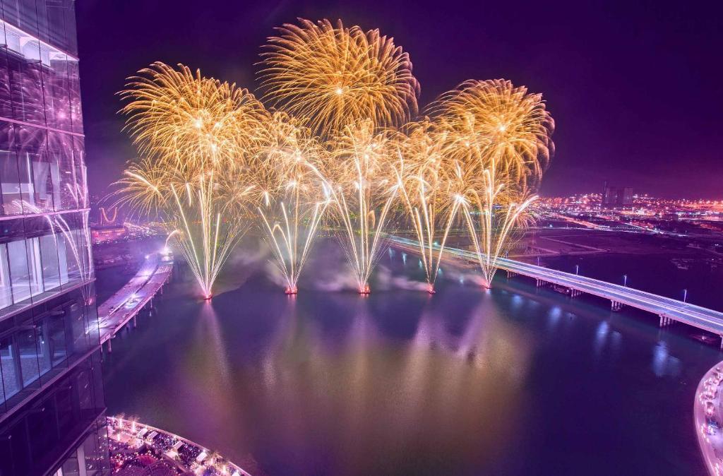 een vuurwerkshow over een rivier met een stad bij Reem 1BR Cozy Nook Apartment Al Maryah 10 Min to Fireworks in Abu Dhabi