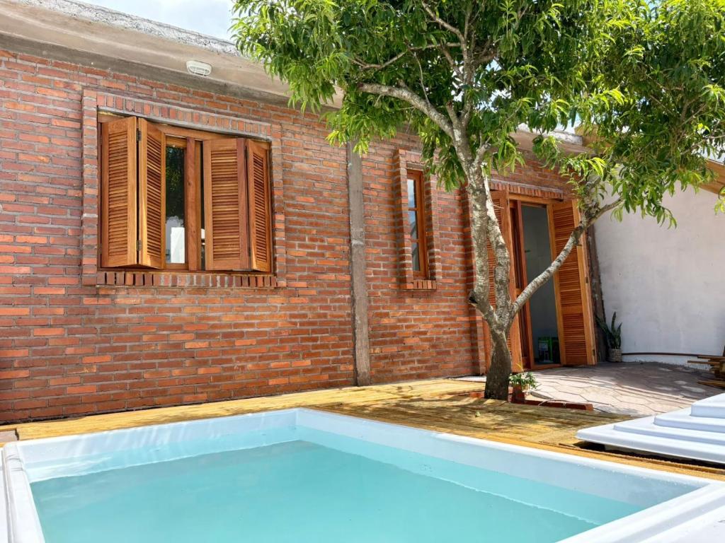 een zwembad voor een bakstenen gebouw met een boom bij Casa quadra-mar com piscina in Rio Grande