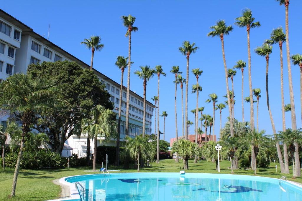 una piscina di fronte a un hotel con palme di Ibusuki Phoenix Hotel a Ibusuki