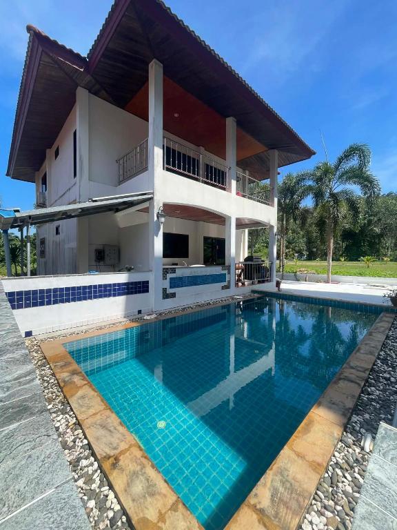 a villa with a swimming pool in front of a house at phu petra villa in Ao Nang 