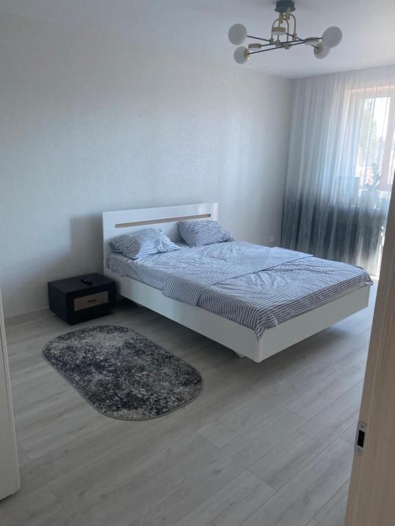 a white bedroom with a bed and a rug at Апартаменты in Izmail