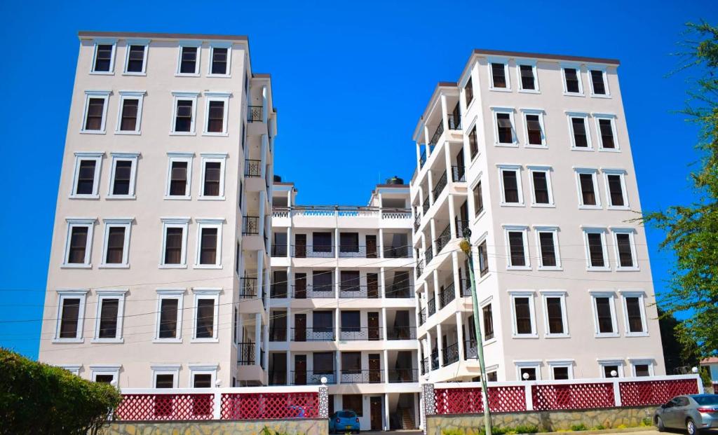 two white apartment buildings against a blue sky at Casses Apartments in Mombasa