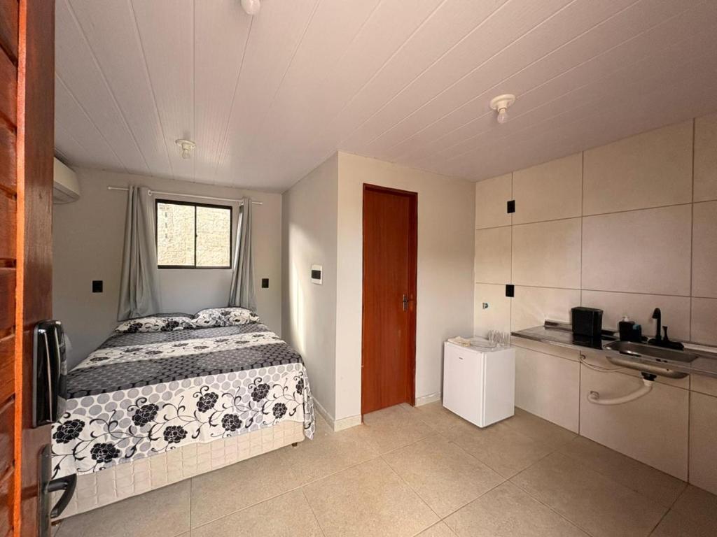 a small bedroom with a bed and a kitchen at Pousada Serena Jacumã in Conde