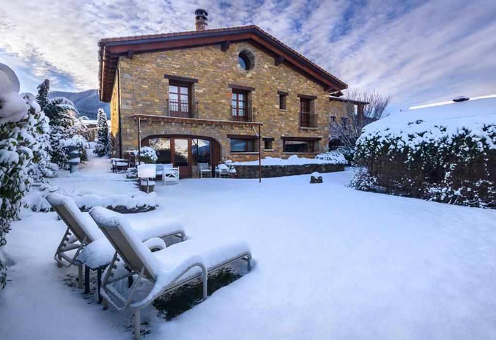 una casa coperta di neve con panchine di fronte di Hotel Boutique Barosse Family & Pet Friendly Roo a Jaca