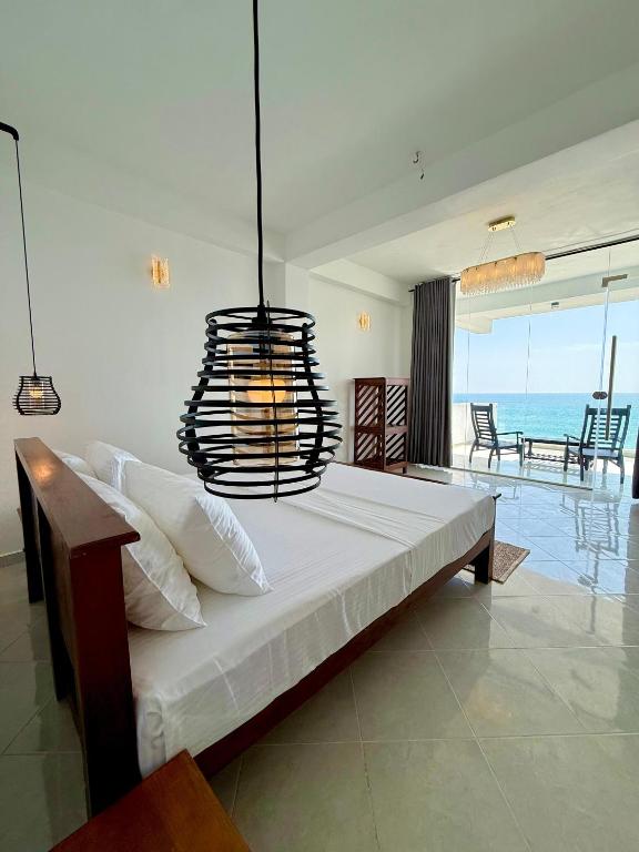 a bedroom with a large bed with a chandelier at Moringa Beach in Mirissa