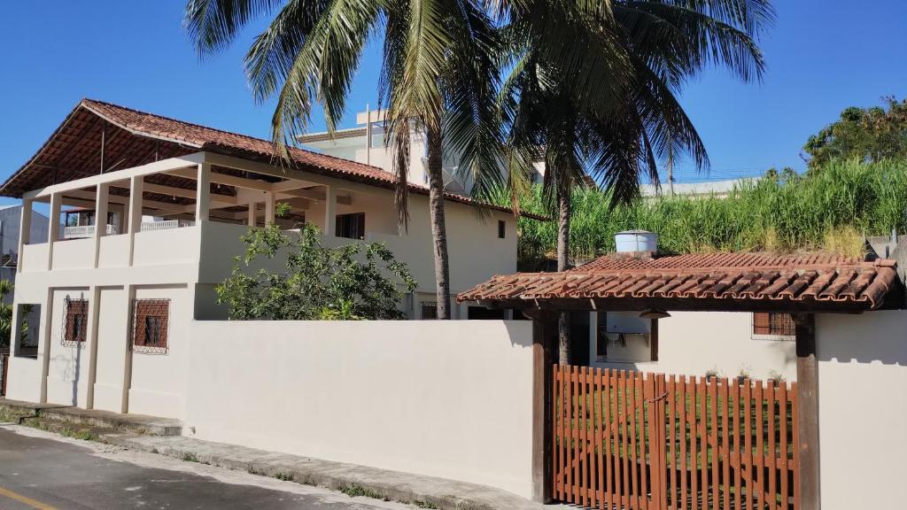 une maison blanche avec une clôture et un palmier dans l'établissement Casa IRIRI, à Anchieta