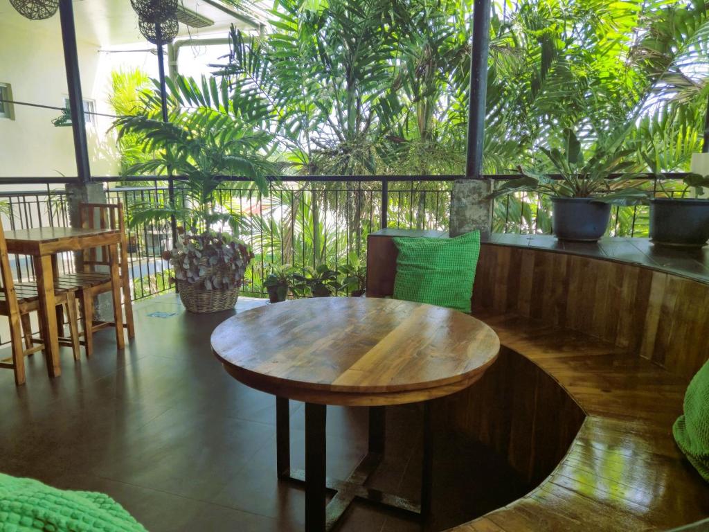 a wooden table and chairs in a room with plants at Green Turtle Backpackers Guesthouse, Puerto Princesa in Puerto Princesa City