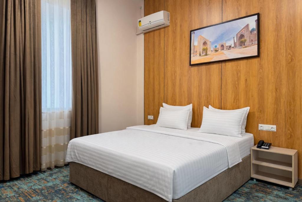 a hotel room with a bed with white sheets at Musafir Hotel in Tashkent