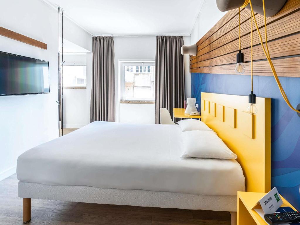 een slaapkamer met een groot wit bed en een tv bij Ibis Styles Lisboa Centro Liberdade NE in Lissabon