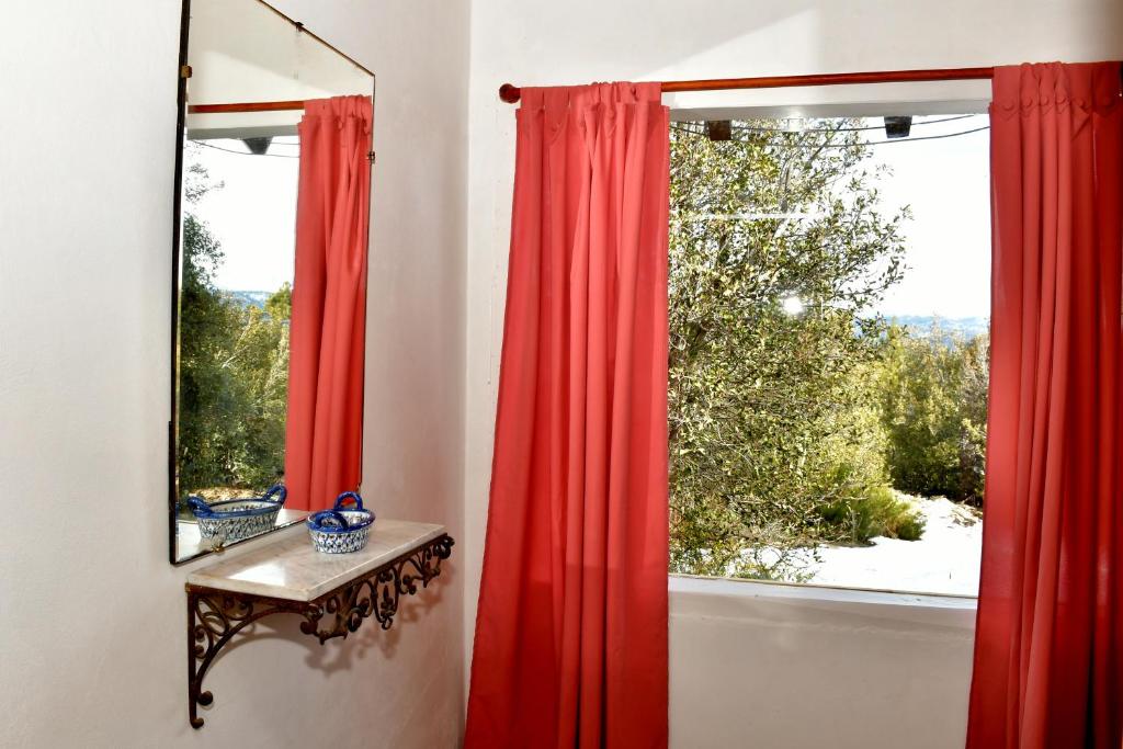a window with red curtains and a table and a mirror at Girgola hospedaje in Villa Pehuenia