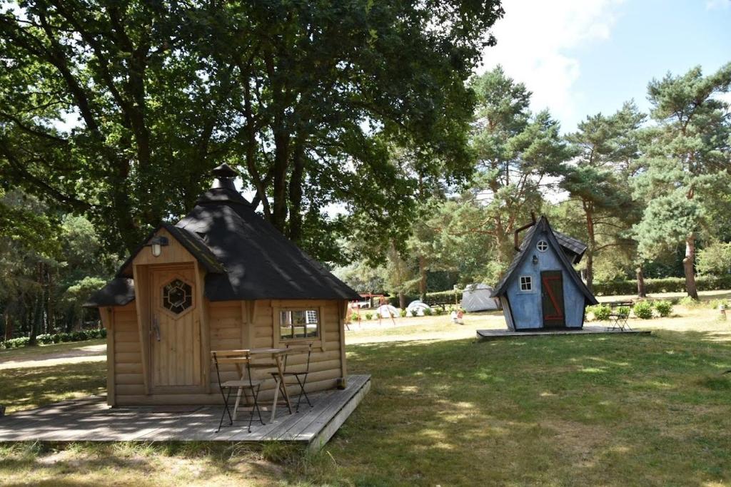 een blokhut en een speelhuisje in een tuin bij camping de brocéliande in Néant-sur-Yvel