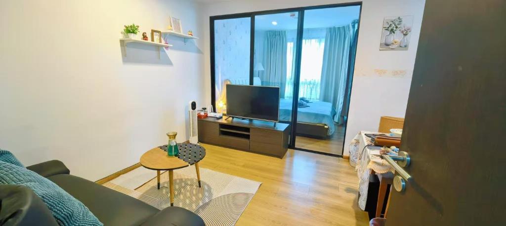 ein Wohnzimmer mit einer Couch, einem Fernseher und einem Tisch in der Unterkunft cen807 in Phuket