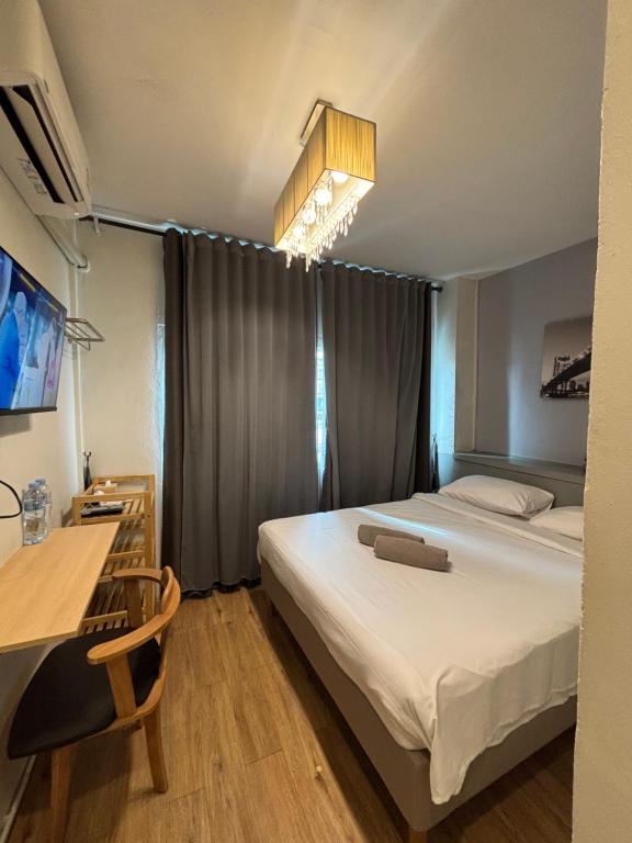 une chambre d'hôtel avec un lit, un bureau et une télévision dans l'établissement Udomsuk Inn & Cafe - BTS Udomsuk, à Bangkok