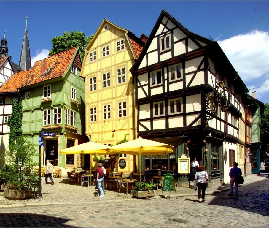 a group of buildings with tables and umbrellas on a street at Schlaf-gut Appartments in Quedlinburg