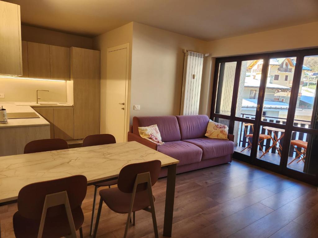 a living room with a table and a purple couch at Valmalenco Home in Chiesa in Valmalenco