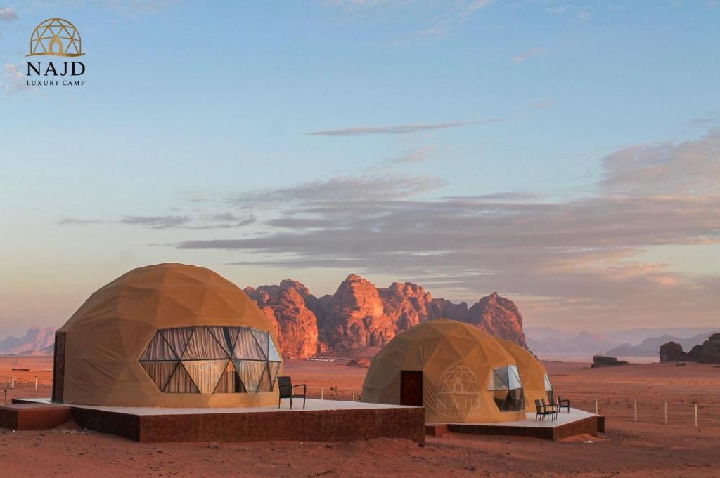 two domes in the desert with rocks in the background at Najd Luxury Camp in Wadi Rum