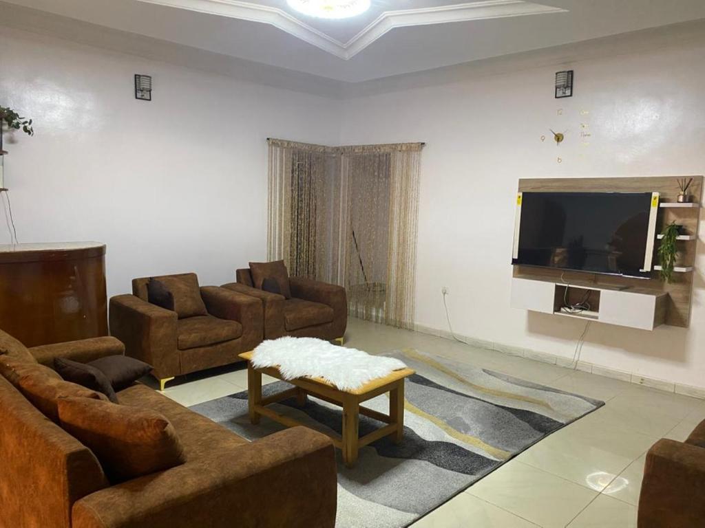 a living room with couches and a flat screen tv at Flamingo 1 spacious solar powered 2 bedroom home with a stocked ready kitchen in Jos