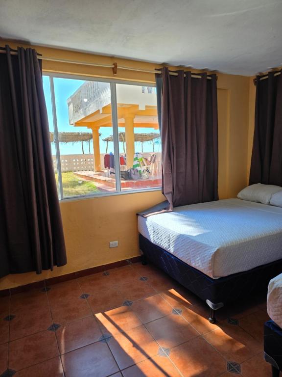 een slaapkamer met een bed en een groot raam bij Hotel y Restaurante Punta Corona in Acajutla