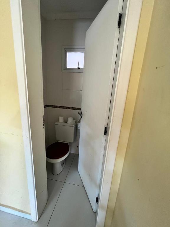 a small bathroom with a toilet and a window at Casa Silva enseada in Guarujá