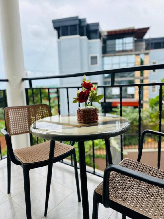 a table with flowers on a balcony with two chairs at Sunset Statehouse View Residence B in Entebbe