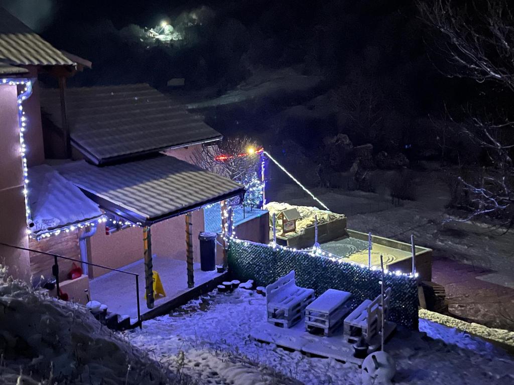 een huis bedekt met licht in de sneeuw 's nachts bij Apartmani Visnja in Crni Vrh