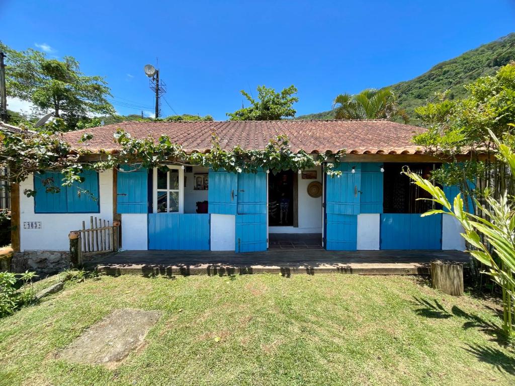 a blue and white house with a hill in the background at Janaína Picinguaba in Ubatuba