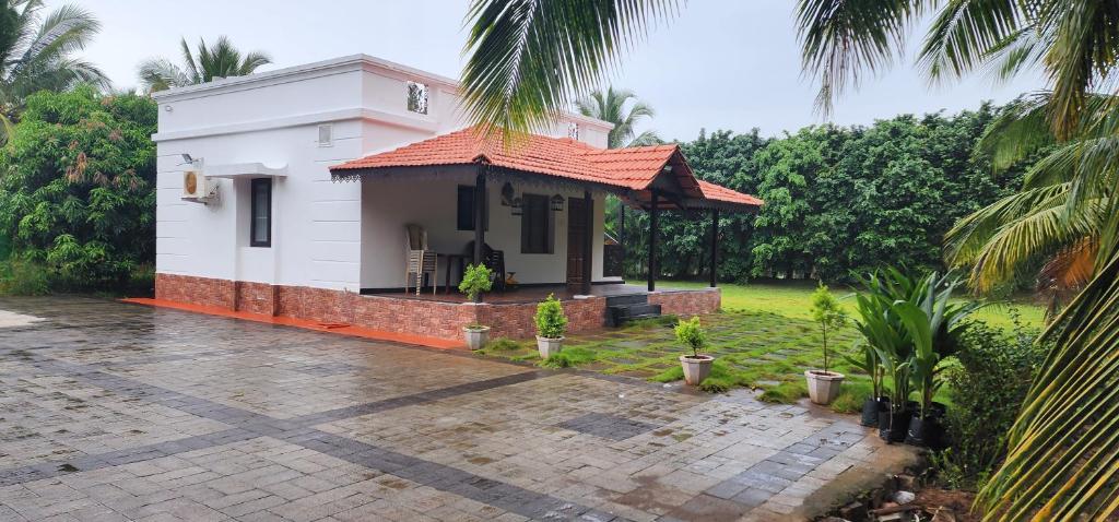 a small white house with a courtyard with palm trees at LBS Farms in Coimbatore
