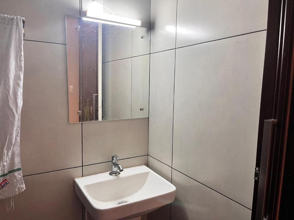 a white bathroom with a sink and a mirror at CloudNine Stay in Sultan Bathery