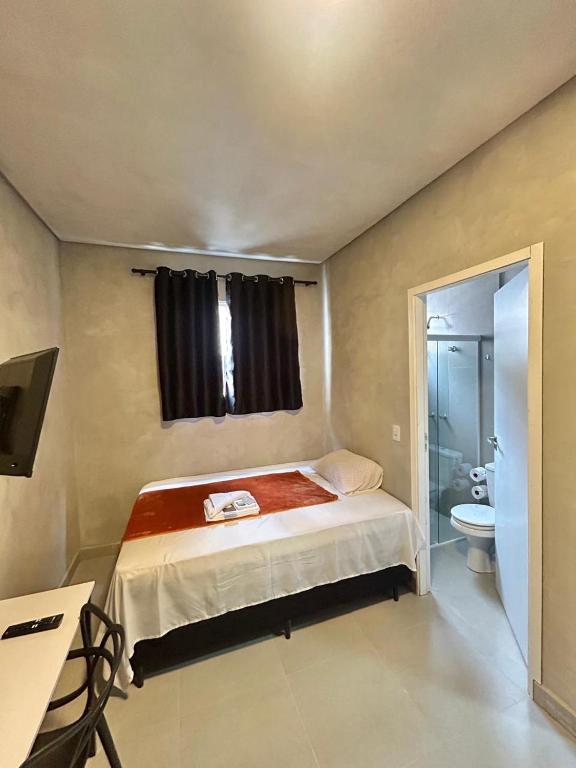 a small bedroom with a bed and a bathroom at #108 Suíte Acolhedora com vaga Centro de Itatiba in Itatiba