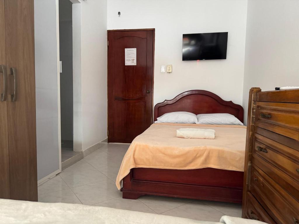 a bedroom with a bed with a tv on the wall at Hotel Casa Colonial Moñitos in Moñitos