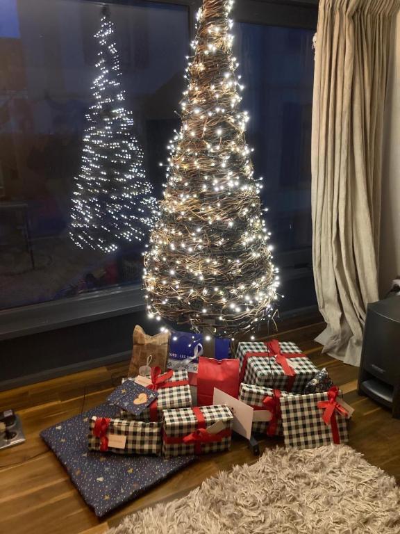 a christmas tree with presents under it in a living room at Gîte 1908 avec GARAGE in Wimereux