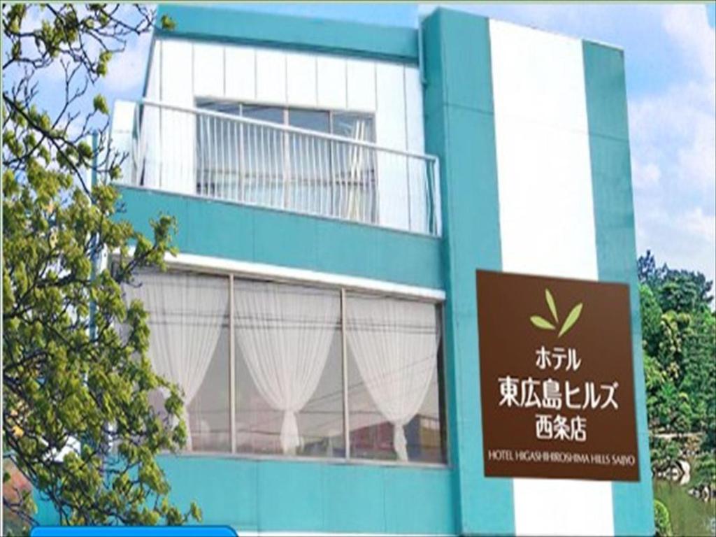 un edificio azul y blanco con un cartel delante en Hotel Higashihiroshima Hills Saijo en Higashihiroshima