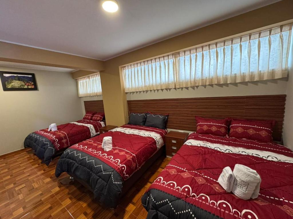 drie bedden in een kamer met rode lakens bij Gran Hotel Real in Huancayo