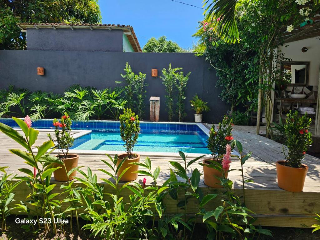 een zwembad in een tuin met potplanten bij Casa Uzêda Trancoso in Porto Seguro