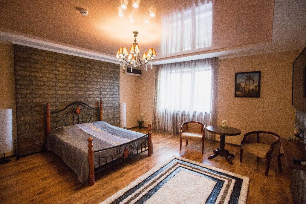 a bedroom with a bed and a table and a window at Park EmpAir Hotel in Pavlodar