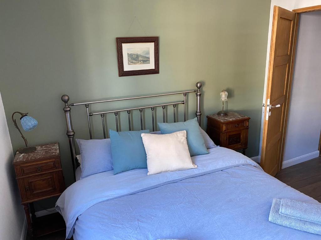 a bedroom with a bed with blue sheets and pillows at La Petite Maison à Beaulieu in Beaulieu-sur-Dordogne