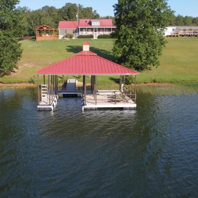 a gazebo with a red roof on the water at Lake House in Phil Campbell