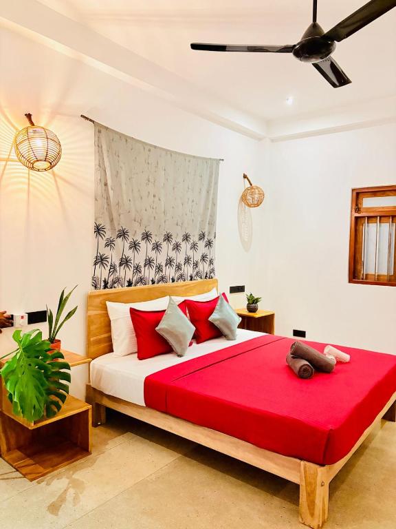 a bedroom with a large bed with a red blanket at Edwin's Ahangama in Ahangama