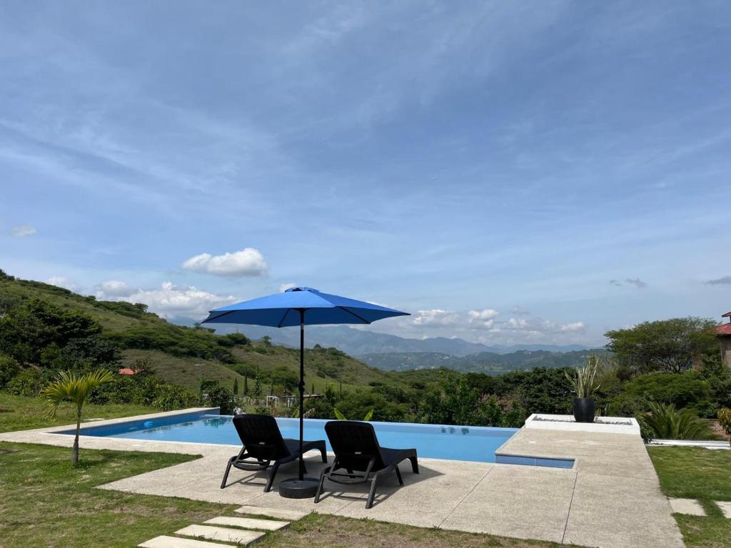 two chairs and an umbrella next to a swimming pool at Casa Vacacional in Loja