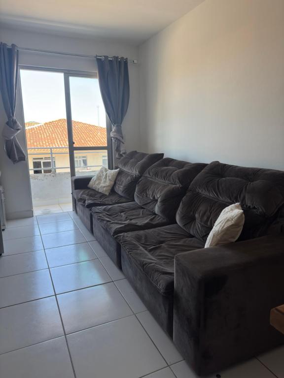 a brown couch in a living room with a large window at Apartamento Pedra Branca in Palhoça