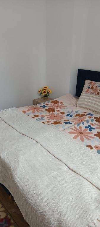 een bed met een witte deken met bloemen erop bij Apartamenty na Witosa in Nowa Sól