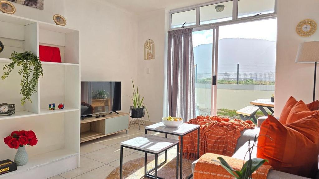 a living room with a couch and a tv at Steps from the beach , Muizenberg home in Muizenberg