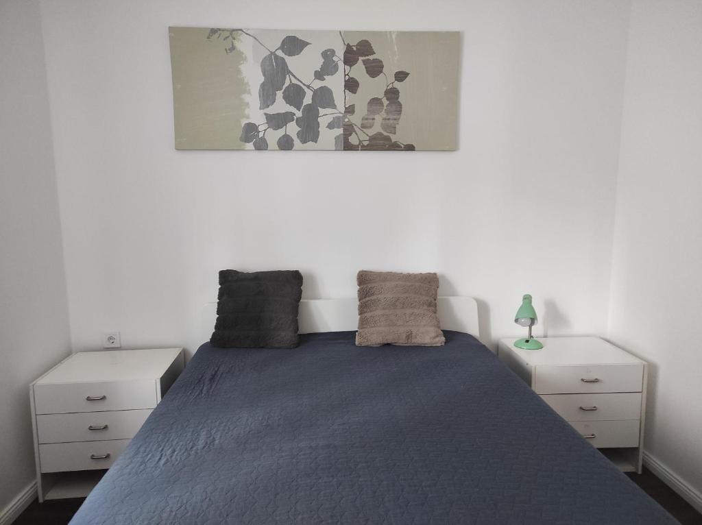 een slaapkamer met een bed met twee witte nachtkastjes bij Garden Home in Törökbálint