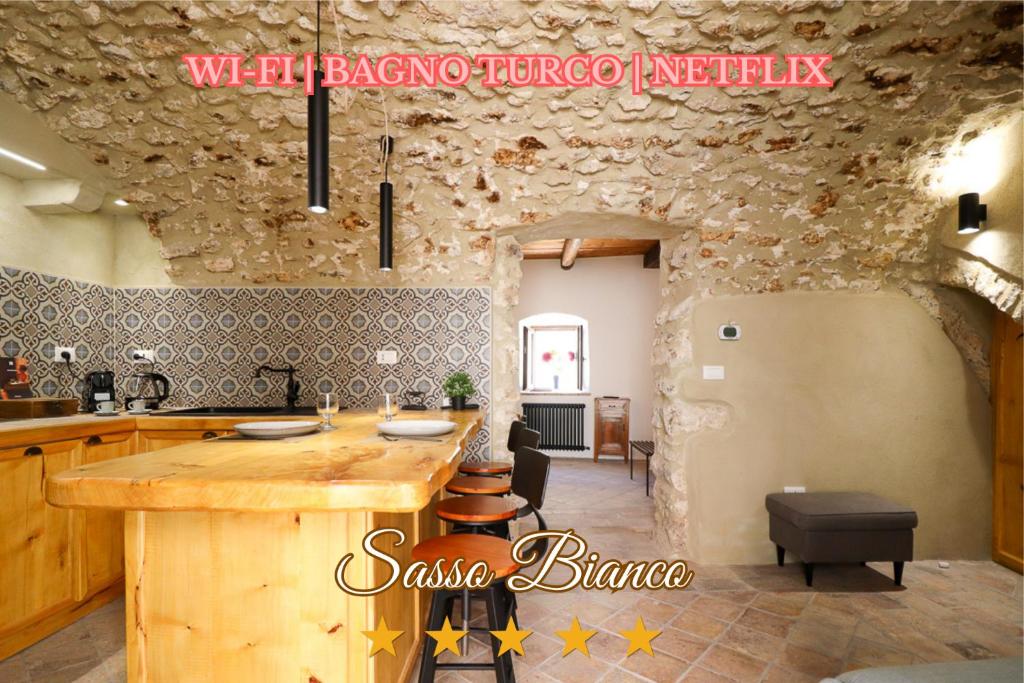una cucina con bancone in legno in un muro di pietra di Sasso Bianco - Bagno Hammam - Doccia emozionale a Santo Stefano di Sessanio