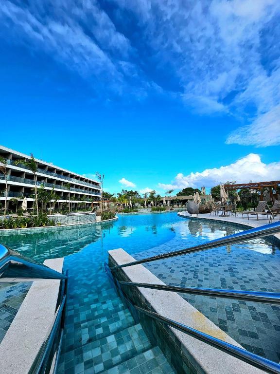a resort swimming pool with blue skies in the background at Luxuoso e sofisticado Beach Class Verano by HM in Ipojuca
