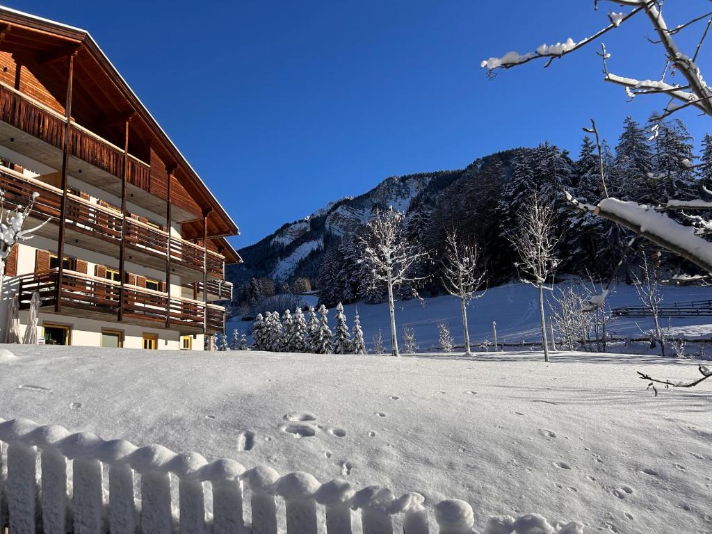 een gebouw met voetafdrukken in de sneeuw naast een berg bij MiraOdle Apartments in Villnoss