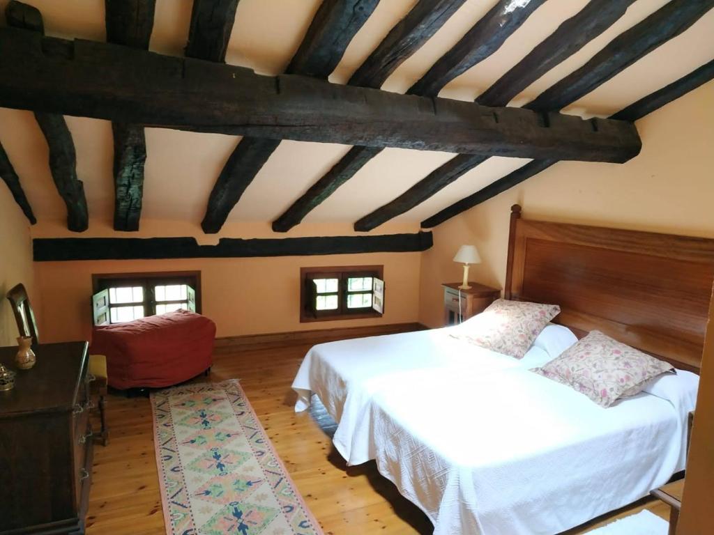 ein Schlafzimmer mit einem weißen Bett und einer Holzdecke in der Unterkunft Casona de Gómez y Terán in Renedo